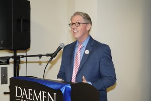 Dr. Greg Ford stands behind a podium speaking into a microphone