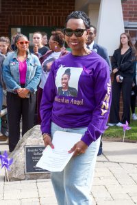 Woman wearing a purple sweatshirt with a photo of her daughter on it, standing in front of a crowd of people