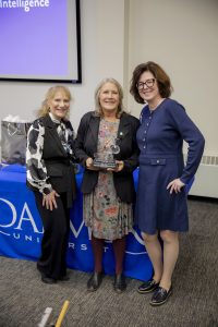 Three women standing together in front of a lecture hall